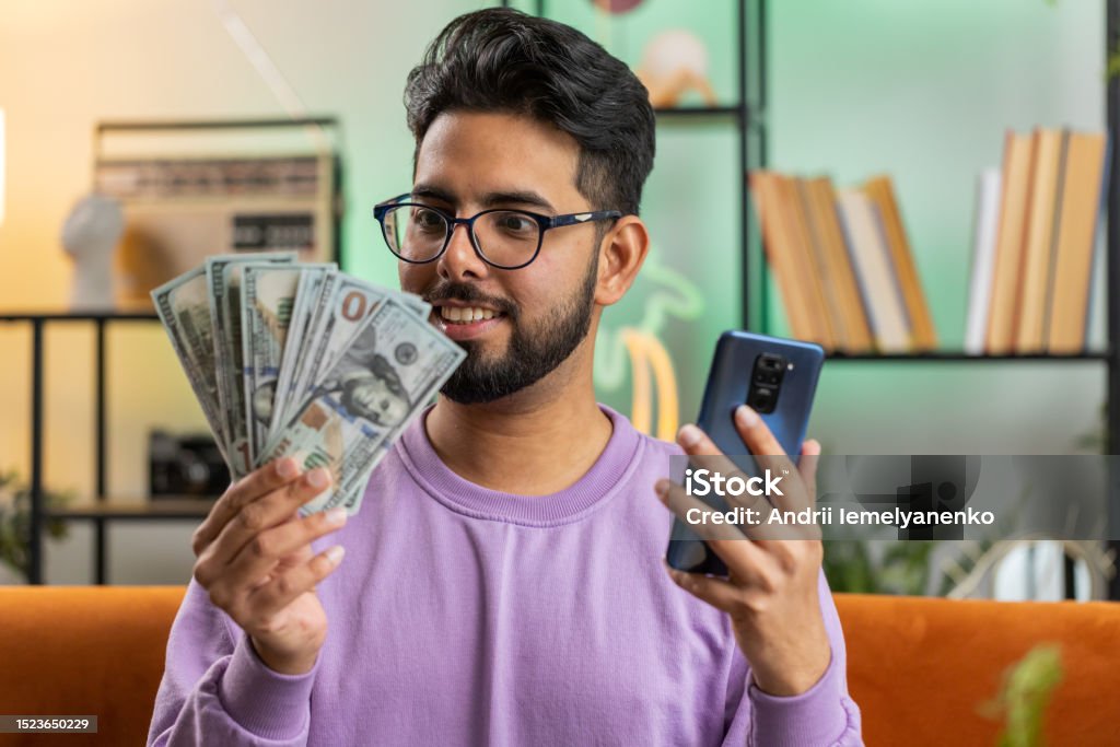 Smiling Happy Indian Man Counting Money Cash Use Smartphone Income Saves Lottery Win Budget At